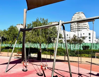a swing set in a park with buildings in the background at Anfa Finance City CFC! Magnifique Apt Tours Végétales, grande terrasse, piscine, parking in Casablanca
