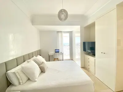 a white bedroom with a bed and a television at Anfa Finance City CFC! Magnifique Apt Tours Végétales, grande terrasse, piscine, parking in Casablanca