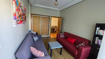 a living room with a red couch and a table at Le doux refuge - à 7 mn de la plage à pieds in Temara