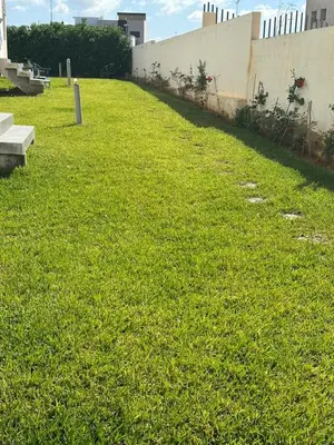 a grassy yard with a wall and a bench at Le doux refuge - à 7 mn de la plage à pieds in Temara