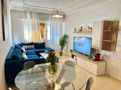 a living room with a blue couch and a glass table at F4 Appartement entièrement neuf au cœur de Témara in Temara