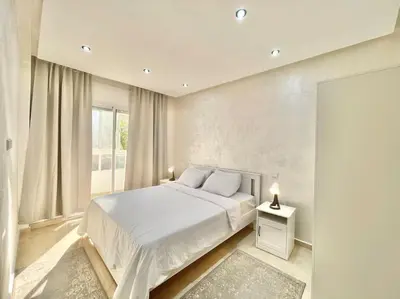 a white bedroom with a bed and a window at F4 Appartement entièrement neuf au cœur de Témara in Temara