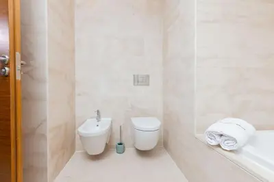 a white bathroom with a toilet and a sink at Aristocratic Abode: Luxurious 2BR Flat in Agdal in Rabat