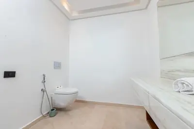 a white bathroom with a toilet and a sink at Aristocratic Abode: Luxurious 2BR Flat in Agdal in Rabat