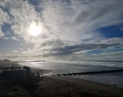 a beach with a cloudy sky and the ocean at Zenata ocean park appartement in Mohammedia