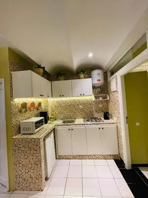 a small kitchen with white cabinets and a tile wall at Beautiful Studio In Casablanca in Casablanca