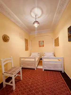 a room with two beds and a chair and a rug at Magnificent studio for two in the center of Casablanca in Casablanca
