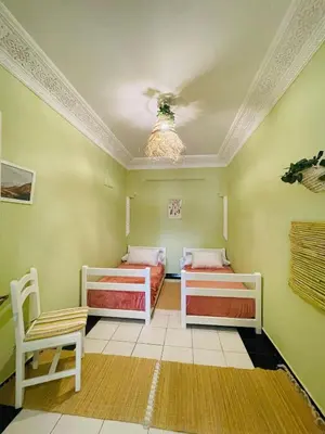 two beds in a room with green walls and a ceiling at Charming Getaway in Casablanca Maroc, Cozy Home with Thoughtful Amenities in Casablanca