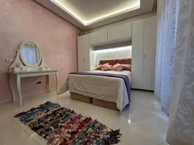 a bedroom with a bed and a mirror and a rug at Belle appartement tout neuf in Bouznika