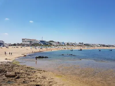 a beach with a group of people in the water at Bouznika Beach appartement de luxe avec piscine in Bouznika