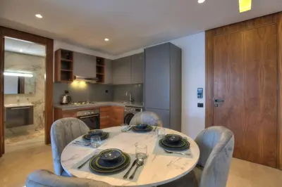 a dining room table with chairs and a kitchen at Appart en face de la tour CFC in Casablanca