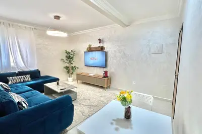 a living room with a blue couch and a tv at T6 Appartement entièrement neuf au cœur de Témara in Temara