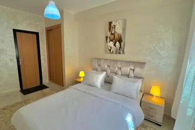 a bedroom with a white bed and a picture of a horse at T6 Appartement entièrement neuf au cœur de Témara in Temara