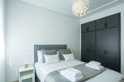 a white bedroom with a large bed and a chandelier at Résidence Windsor in Casablanca