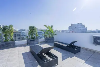 a rooftop patio with furniture and a white wall at Résidence Palm - Palmiers in Casablanca