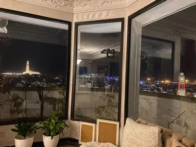 a room with three windows with a couch and a city at اقامة الهام in Casablanca