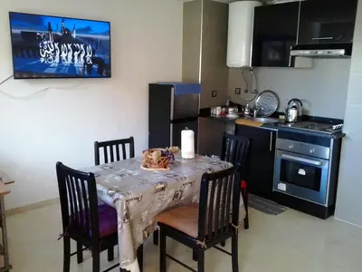 a kitchen with a table with chairs and a kitchen with a stove at Appartement Bella Vista in Bouznika
