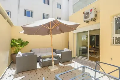 a patio with an umbrella and chairs and a table at Résidence Doribel in Casablanca