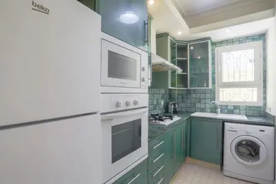 a kitchen with green cabinets and a washer and dryer at Résidence Doribel in Casablanca