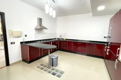 a kitchen with red cabinets and a table in it at Luxury villa with private pool in Casablanca