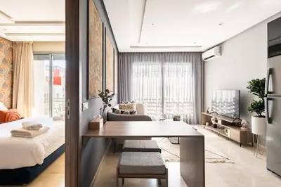 a living room with a dining table and a bedroom at The Twenty-Six Palmier by IB Signature - Design 1Bedroom Apt with Wifi, Parking, Self check-in, 24 x7 Security - City View with terrace - Walk to Cafes! City Centre, Tram in Casablanca