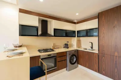 a kitchen with wooden cabinets and a washer and dryer at Keyless Smart door/ New /Free parking/Central in Casablanca