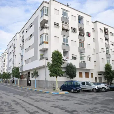 a white building with cars parked in a parking lot at Cozy appartement à Mohammedia in Mohammedia