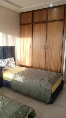 a bedroom with a large bed with wooden cabinets at Beautiful 3BR apartment in Hay Riad Rabat in Rabat