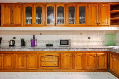 a kitchen with wooden cabinets and a microwave at Spacious Harhoura Villa: Perfect for Families (5min to Beach) in El Harhoura