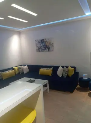 a living room with a blue couch and yellow pillows at Cocon cozy à Mansouria Mer, piscines et nature in Mansouria