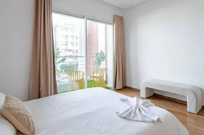 a white bedroom with a bed and a large window at TT Holidays Hay Riad Prestigia in Rabat