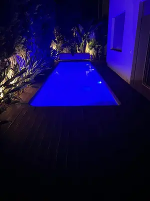 a blue swimming pool in a backyard at night at Villa de Luxe piscine privée in Casablanca