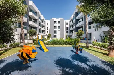 a playground in front of a large apartment building at ZS house harhoura vue sur piscine in Temara