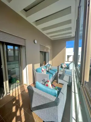 a balcony with couches and chairs on a building at Heaven Beach SIDI RAHAL in Sidi Rahal