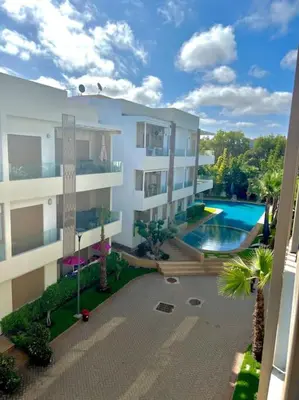 an apartment building with a swimming pool and palm trees at Heaven Beach SIDI RAHAL in Sidi Rahal