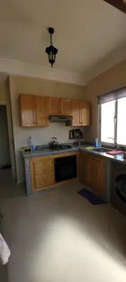 an empty kitchen with wooden cabinets and a window at Bel appartement avec vue sur mer Sidi Rahal in Sidi Rahal