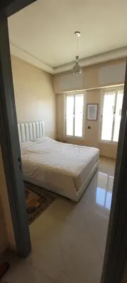 a bedroom with a large bed and two windows at Bel appartement avec vue sur mer Sidi Rahal in Sidi Rahal