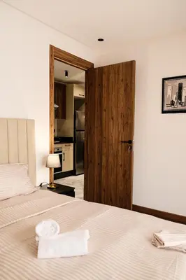 a bedroom with a white bed with a wooden door at New Apartment Casablanca City Center Maarif in Casablanca
