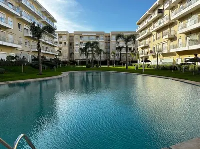 a large swimming pool in front of a building at Jolie Appartement 2 chambres / vue piscine in Bouznika