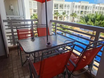 a table with chairs and an umbrella on a balcony at superbe appartement vue piscine in Bouznika