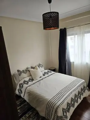 a bedroom with a bed with a white blanket and a window at Bel appartement en bord de mer in Casablanca