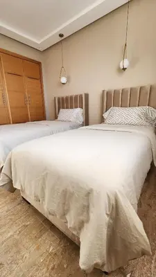 a bedroom with two beds with white sheets at Beautiful beachfront apartment in Rabat