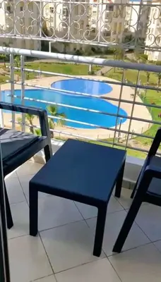 a blue bench sitting on a balcony with a swimming pool at Appartement avec piscine in Bouznika