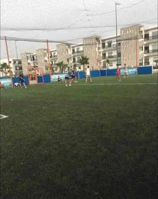 a group of people playing a game of frisbee on a field at Nice Apartment in Blanca Beach in Sidi Rahal