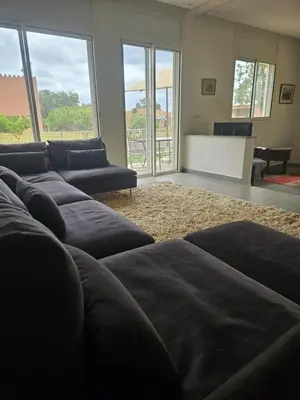 a living room with couches and a table and windows at Premium farmhouse with pool in Rabat