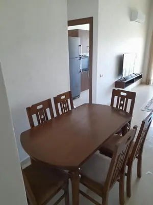 a dining room table with chairs and a refrigerator at Vacances Soleil Piscine & Plage Bouznika in Bouznika