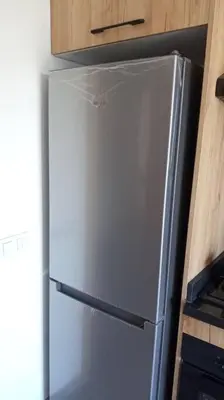 a stainless steel refrigerator in a kitchen with wooden cabinets at Heaven Beach Front Apartment 2 Br in Sidi Rahal