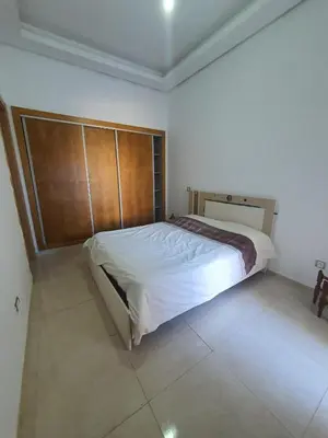 a bedroom with a large bed with a wooden headboard at Résidence Balnéaire, Appartement 2 Chambres in Mansouria