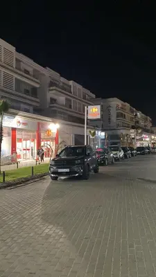 a black car driving down a street at night at Résidence Balnéaire, Appartement 2 Chambres in Mansouria