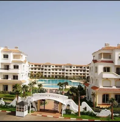 a large building with a swimming pool in front of it at Complex garden beach2 sidi rahal in Sidi Rahal